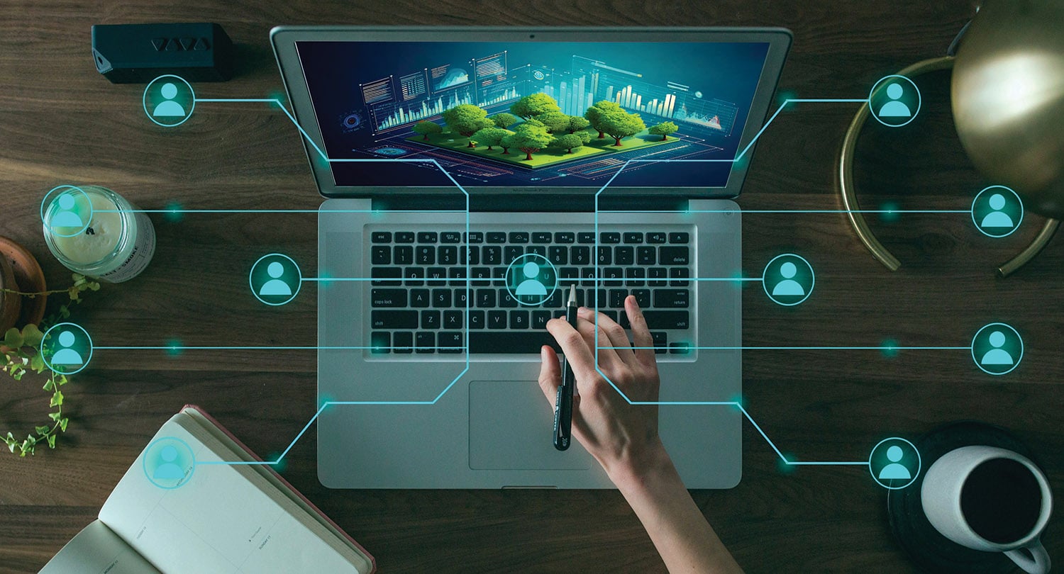 A person's hand holding a pen on a laptop with trees on the screen.